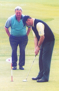 Iain prime putting with guide brian wilson looking on